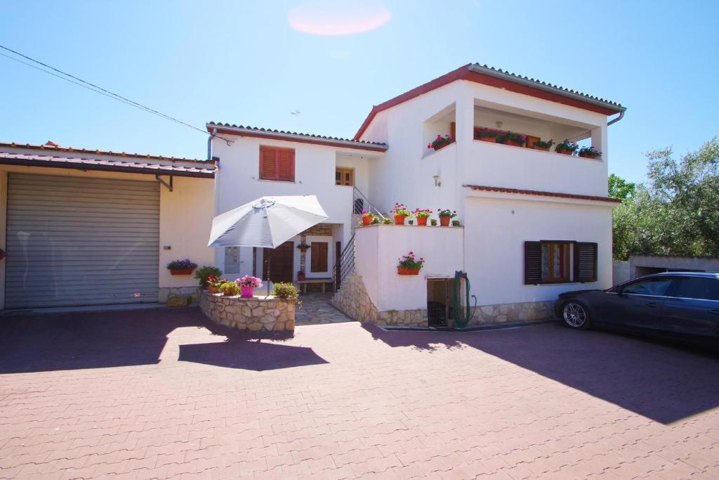 une maison blanche avec une voiture garée devant elle dans l'établissement Holiday apartment Silvija, Loborika, à Loborika