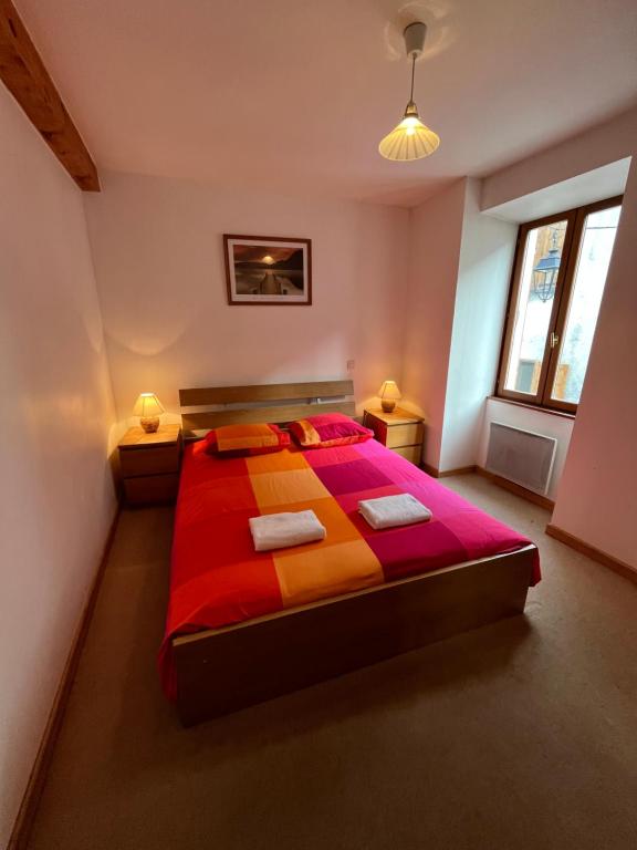 ein Schlafzimmer mit einem Bett mit einer roten und orangefarbenen Decke in der Unterkunft Townhouse The Granary Bourg d’Oisans in Le Bourg-dʼOisans