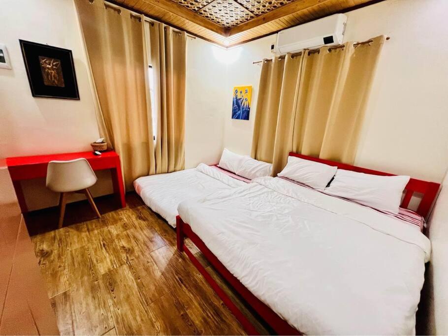 1 dormitorio con 2 camas y escritorio con silla en Delia's Guest House en Isla de Mactán