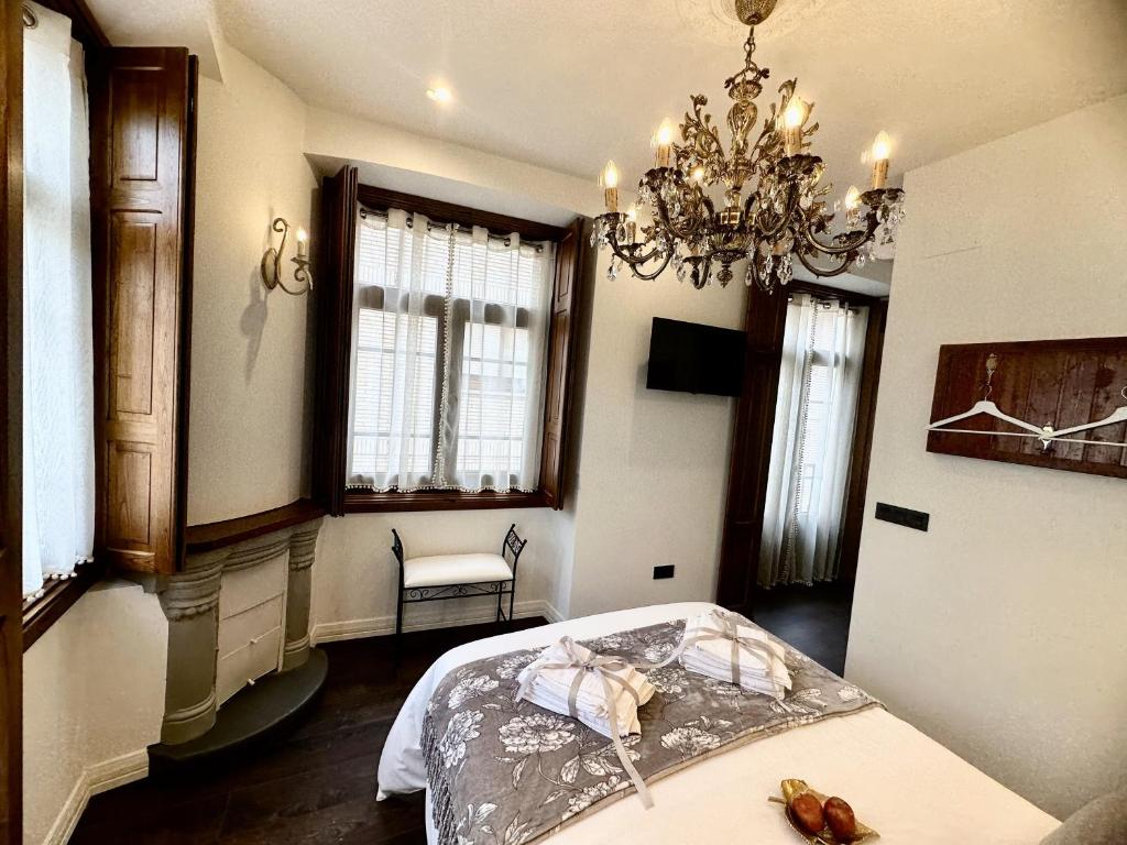 a bedroom with a bed and a chandelier at CLAREN´S BOUTIQUE ROOMS in Cangas del Narcea