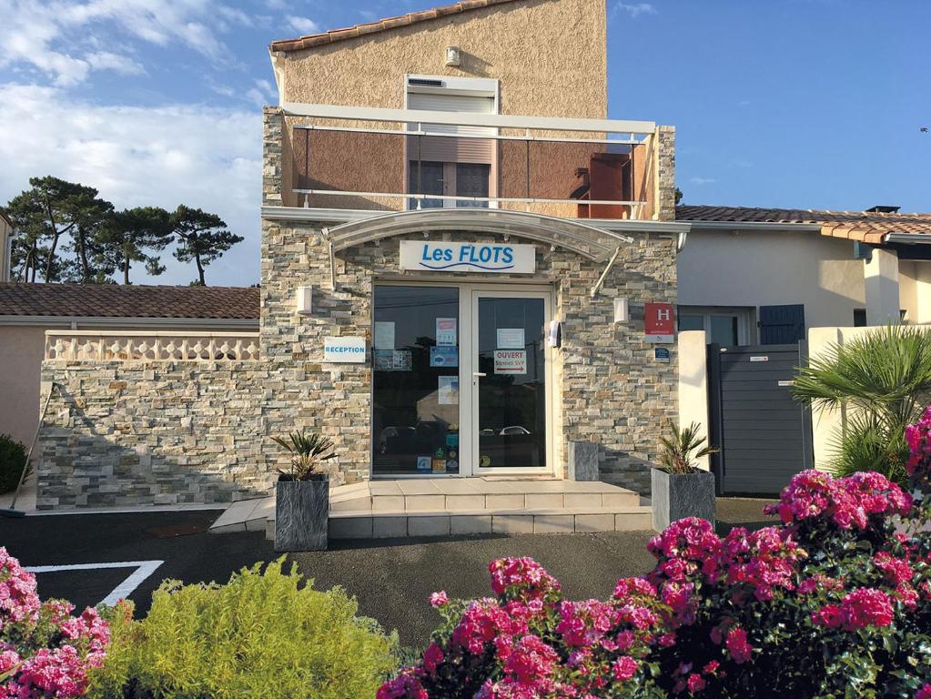 una tienda de usos delante de una casa con flores en Hôtel Résidence Les Flots, en Saint-Palais-sur-Mer