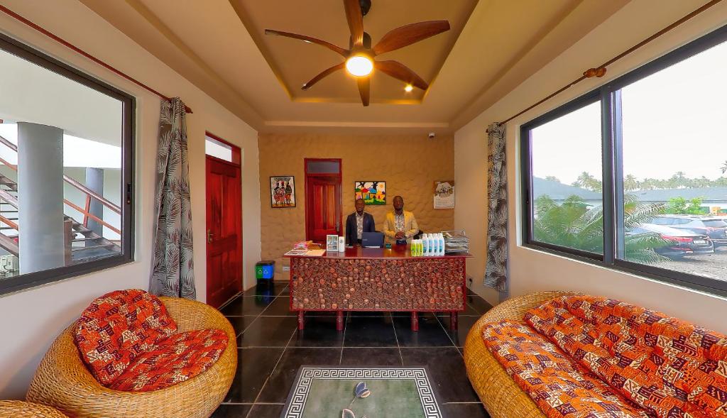 een kamer met twee personen aan een tafel met ramen bij Lemon Beach Resort in Elmina