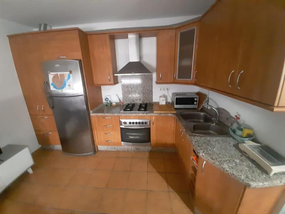 a kitchen with wooden cabinets and a stainless steel refrigerator at Casa mis Nietas in San José