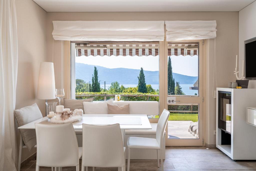 ein Esszimmer mit einem weißen Tisch und Stühlen sowie einem großen Fenster in der Unterkunft Apartment Wieser Garda Lake in Gargnano