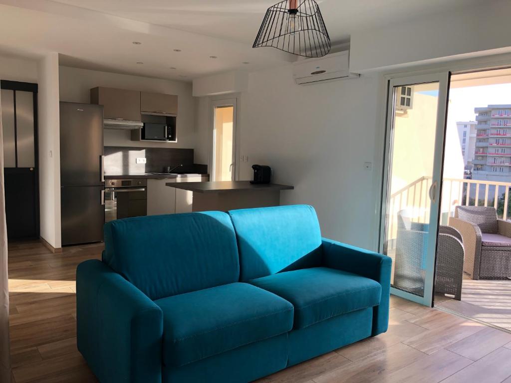 - un canapé bleu dans un salon avec une cuisine dans l'établissement Spacieux studio entièrement rénové, à Ajaccio