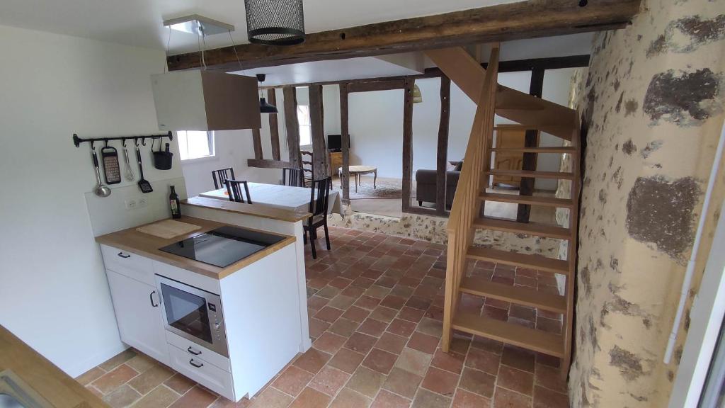 a kitchen with a staircase leading to a living room at Petite maison de campagne in La Bazoge