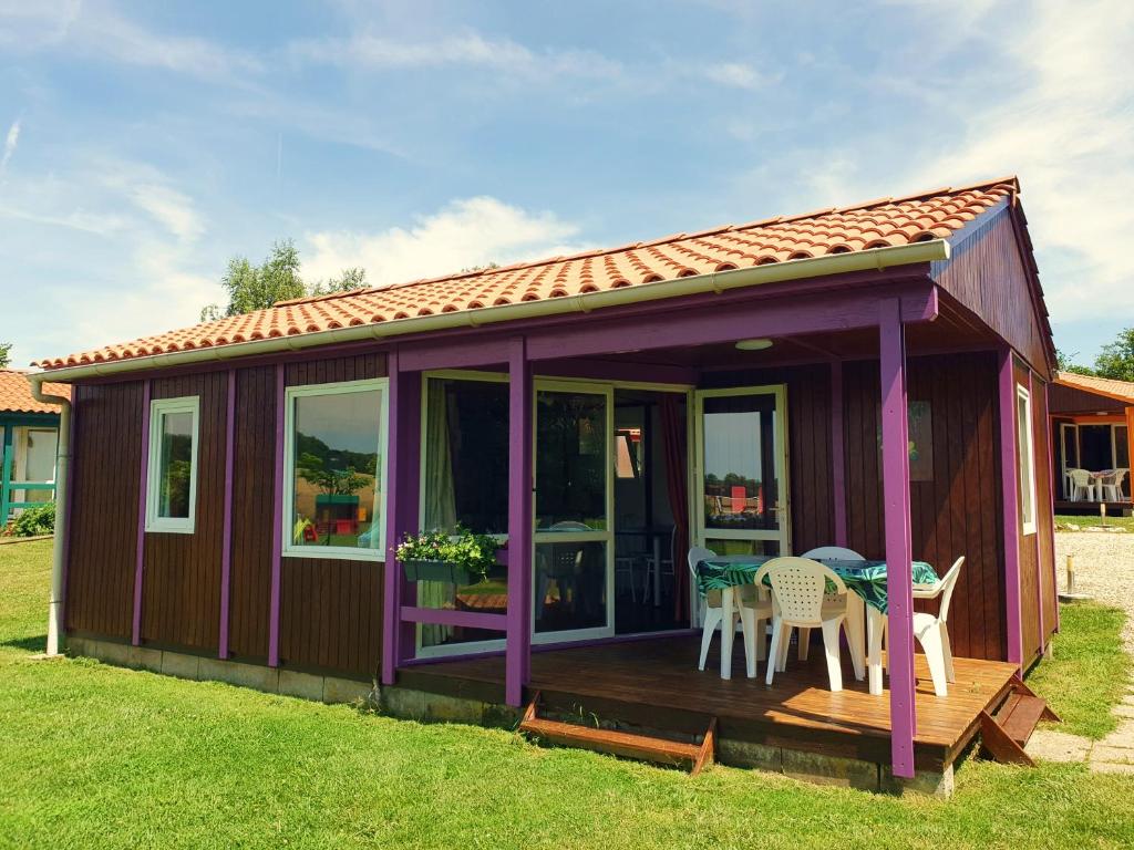 une cabine violette avec une terrasse dotée d'une table et de chaises dans l'établissement Les Chalets du Quignon, à Autry-le-Châtel