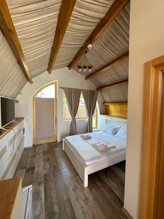 a bedroom with a white bed and a wooden ceiling at Complex Andris in Murighiol