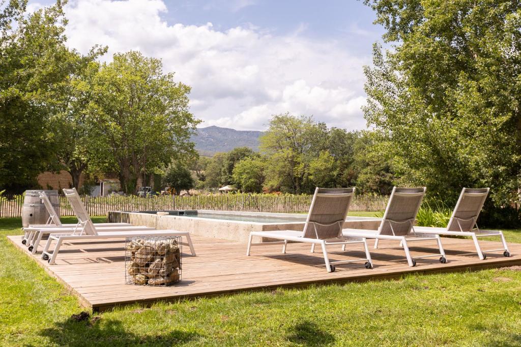 Tres sillones y una mesa en una terraza de madera. en La Bergerie, en Argelès-sur-Mer