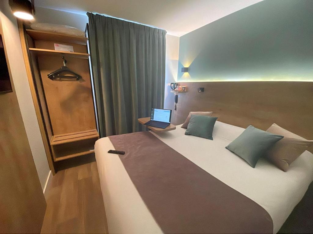 a bedroom with a large bed with a laptop on it at Kyriad Montpellier Sud - A709 in Montpellier