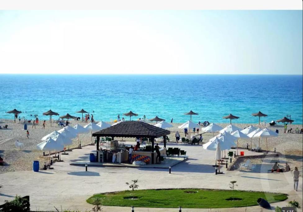 a beach with a group of umbrellas and the ocean at Luxury Chalet With Roof at Nice 4 North coast kilo 75 نيس ٤ in Dawwār Abū Duray‘ah ‘Abd al Karīm