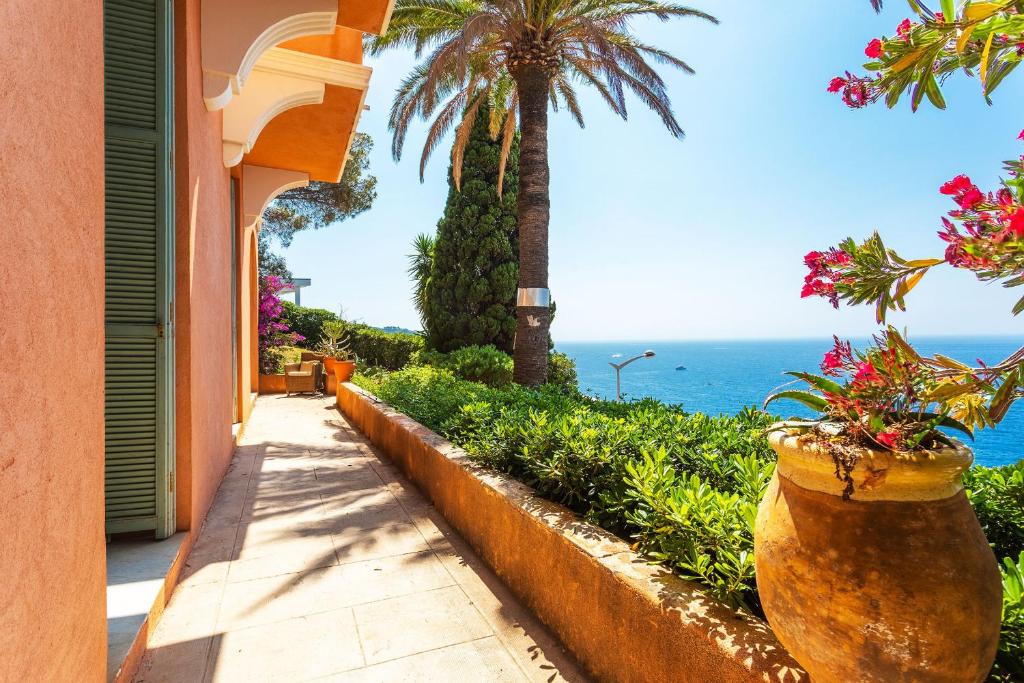 een huis met palmbomen en de oceaan op de achtergrond bij Villa Reve d azur vi4353 by Riviera Holiday Homes in Nice