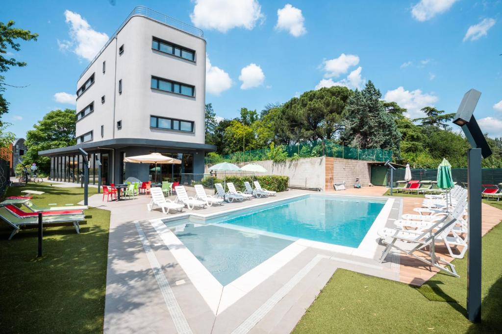 un hôtel avec une piscine, des chaises et un bâtiment dans l'établissement Hotel Stadio & Spa, à San Bonifacio