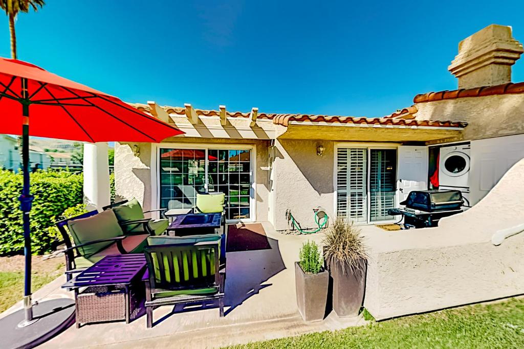 a patio with chairs and a red umbrella at Mesquite Country Club Condo O64 - Permit # 4552 - 7 night minimum stay in Palm Springs