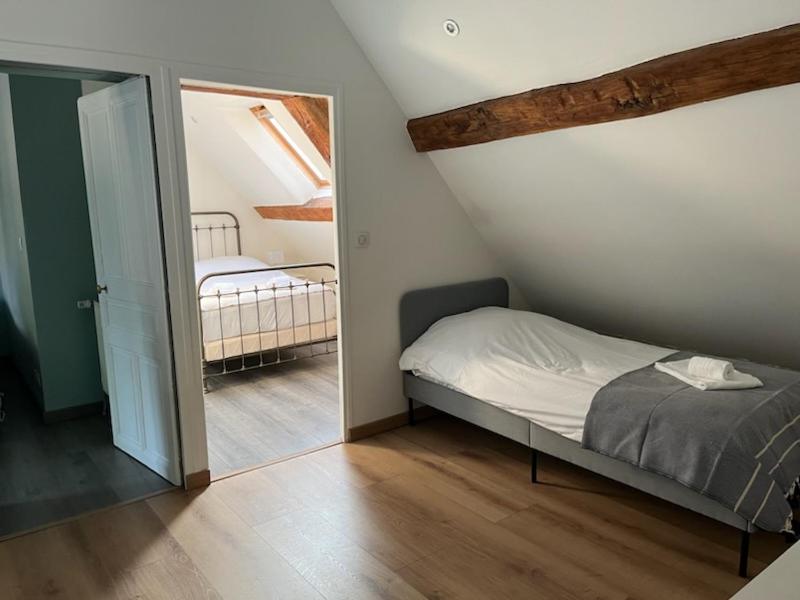 ein kleines Schlafzimmer mit einem Bett und einem Spiegel in der Unterkunft La Maison de Zoé in Saint-Denis-sur-Loire