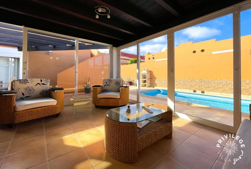 a living room with chairs and a table and a pool at Villa Privilege Sun in Corralejo