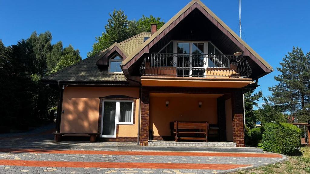 ein kleines Haus mit einem Balkon und einer Veranda in der Unterkunft U Lipińskich - Dom nad jeziorem in Ostrzyce