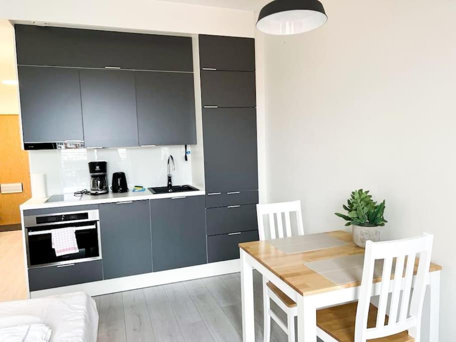 een keuken met grijze kasten en een tafel en stoelen bij Kotimaailma Oulu Apartments Kasarmintie in Oulu
