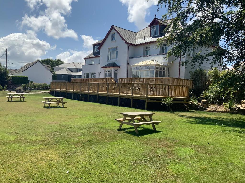 two picnic tables in front of a large house at St Merryn in Carbis Bay