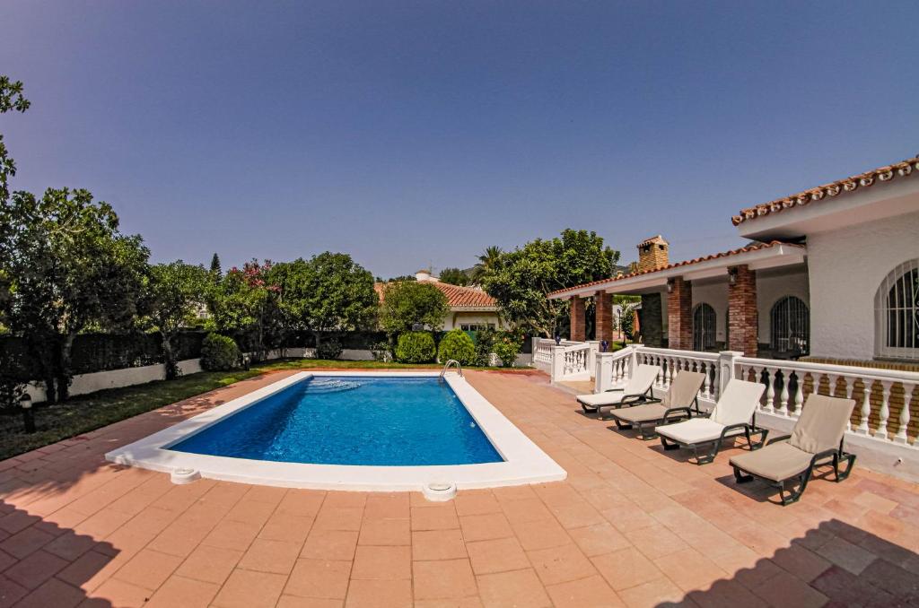 basen z krzesłami i dom w obiekcie Villa Yanna w mieście Benalmádena
