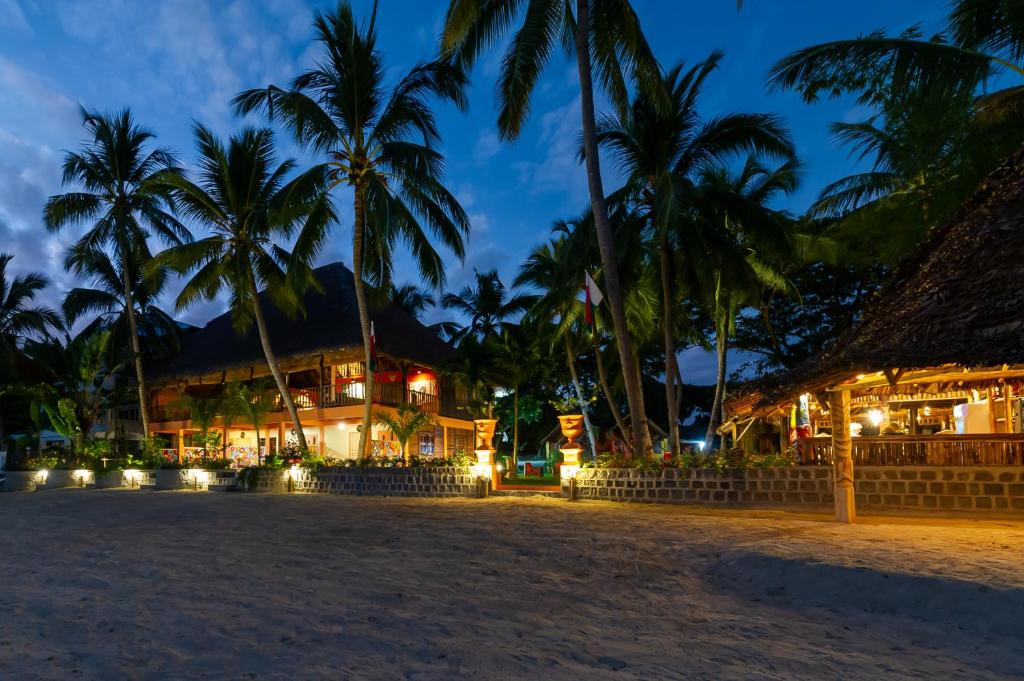 a resort on the beach at night with palm trees at La Plage de Le Zahir in Nosy Be
