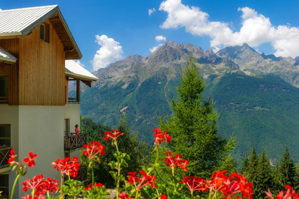 une vue sur les montagnes depuis une maison avec des fleurs rouges dans l'établissement Résidence Capfun Couleurs Soleil, Oz en Oisans, à Oz