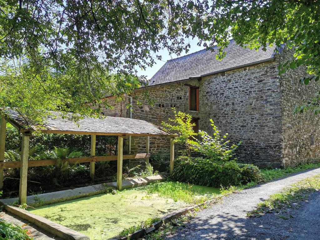 kamienny budynek z drewnianym pawilonem przed nim w obiekcie Breton stone cottage with a garden near the river w mieście La Vicomté-sur-Rance