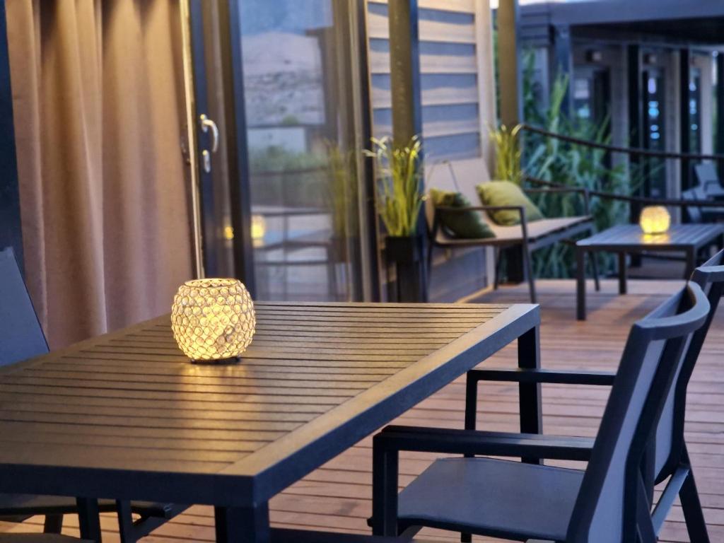 Olive Mobile Home, Terra Park SpiritoS في كولان: طاولة خشبية مع كراسي ومصباح على سطح السفينة