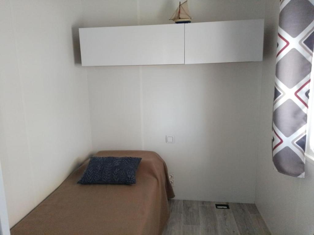a small bedroom with a bed and a white wall at Mobil home neuf en Bretagne sud in Guérande