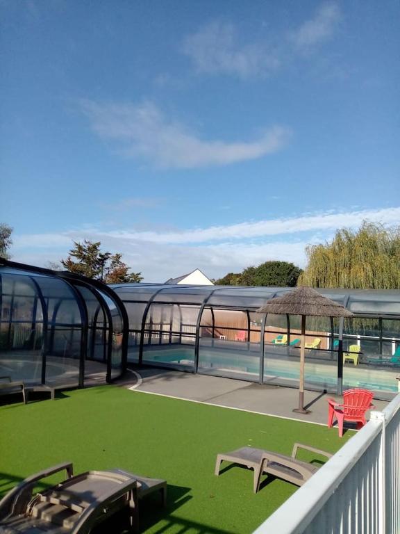 a balcony with two chairs and an umbrella and a pool at Mobil home neuf en Bretagne sud in Guérande