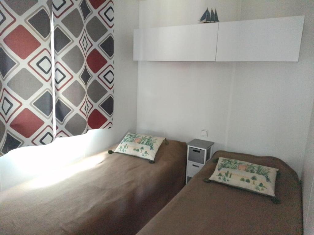 a small bedroom with two beds and a wall at Mobil home neuf en Bretagne sud in Guérande