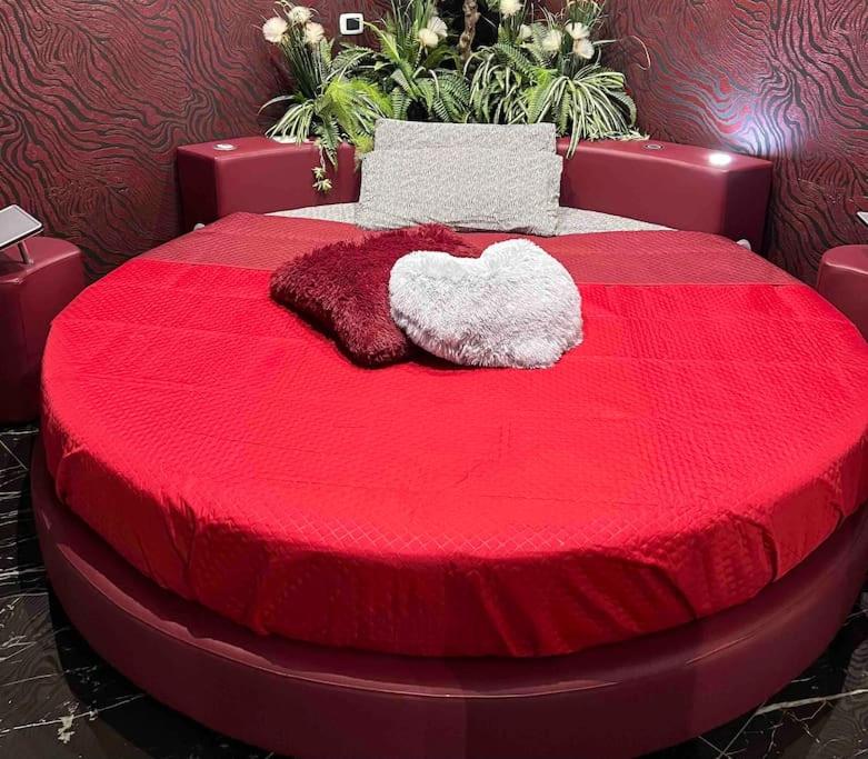 un letto rosso con due cuscini sopra di DEVILTHON SUITE NETTUNO a Nettuno