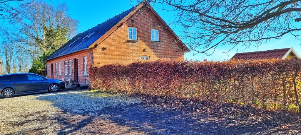 een bakstenen gebouw met een auto ervoor geparkeerd bij Quiet and cozy apartment close to nature in villa. in Tilst