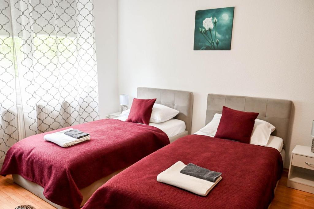 two beds in a room with red sheets and towels at Rožės Namai B&B in Raseiniai