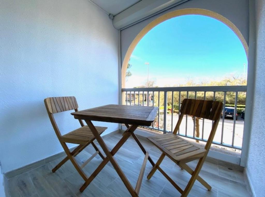 une table en bois et deux chaises sur un balcon dans l'établissement Studio rénové avec Terrasse 100m plage 50m Port, à Mauguio