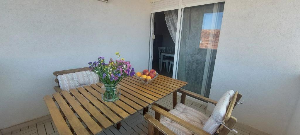 una mesa con un jarrón de flores en el balcón en Apartments TERRAeSAL, en Zadar