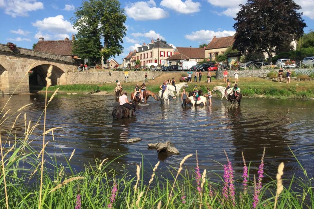 a group of people riding horses in the water at Gite Au Fil de lEau 
