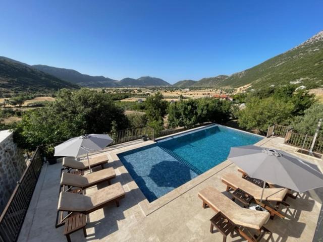 a swimming pool with chairs and umbrellas next to at Bezirgan Inn Kalkan in Islamlar