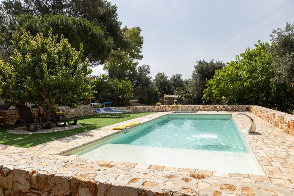 a swimming pool in a yard with a stone wall at trullo nonna netta con piscina idromassaggio e area giochi in Ceglie Messapica