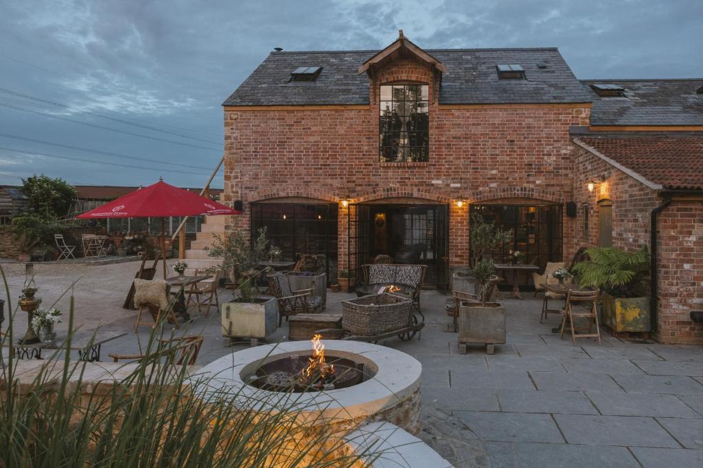 a patio with a fire pit in front of a brick building at Outbuildings Dorset in Bridport