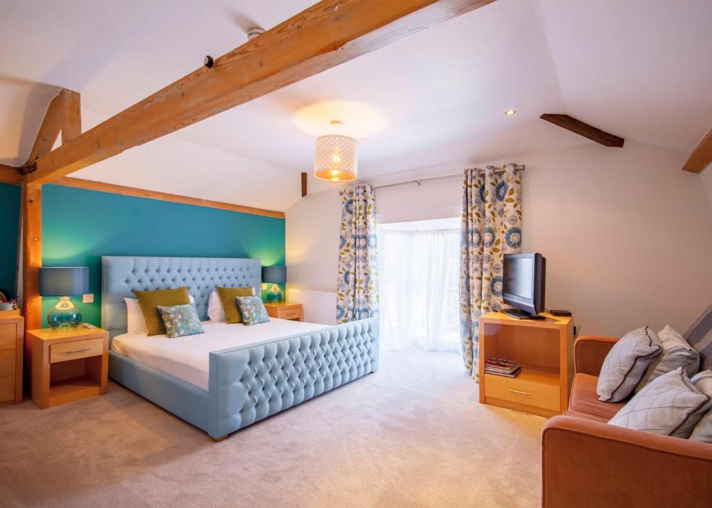 a bedroom with a bed and a couch and a tv at The Highworth Hotel in Swindon
