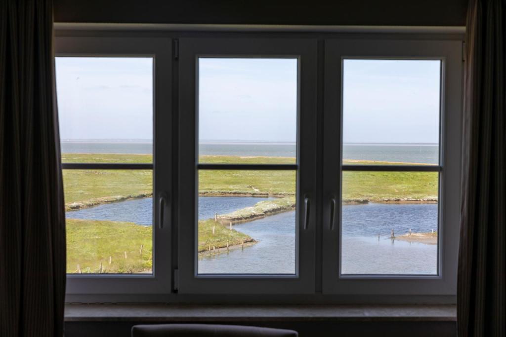 una ventana con 3 vistas al océano en Anker's Hörn - Hotel & Restaurant auf der Hallig Langeness, en Langeneß