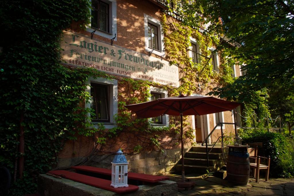 un bâtiment avec un parasol devant lui dans l'établissement Das Forsthaus Hotelapartments, à Bad Schandau