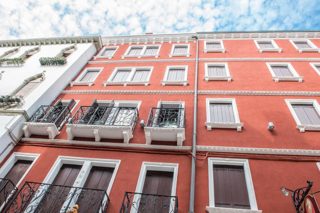 キオッジャにあるPiccola Venezia Apartmentsの白い窓とバルコニーが備わる赤レンガ造りの建物