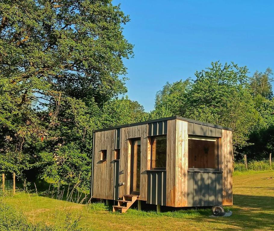 a small wooden cabin in a field with trees at L’Escargoterie de la Forge - Immersion Champêtre in Uzemain