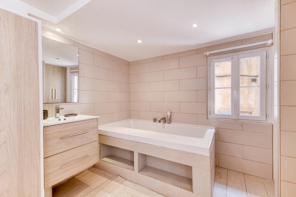 baño con bañera, lavabo y ventana en Pick A Flat&#39;s Apartment in Saint-Tropez- Rue du Portail Neuf, en Saint-Tropez
