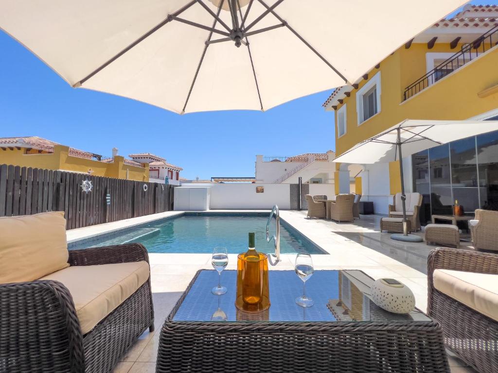 a patio with a table with wine glasses and an umbrella at Villa Sam in Murcia