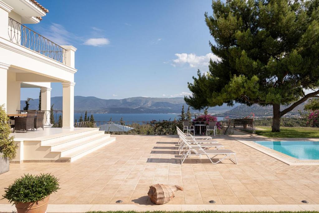 a house with a swimming pool and a tree at Villa Fantasia Isthmia in Isthmia