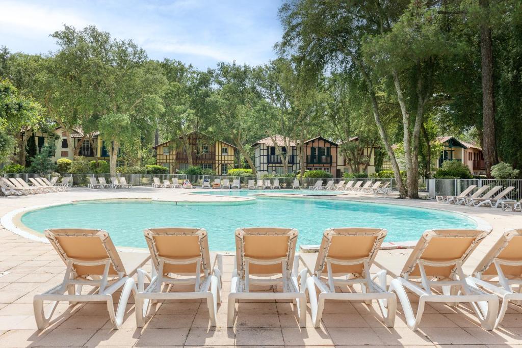 a group of chairs sitting around a swimming pool at Villa au coeur du golf in Moliets-et-Maa