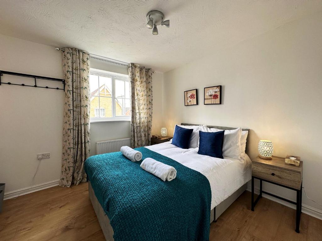 a bedroom with a large bed with blue pillows at Layla's Place in Hertfordshire in Chesfield